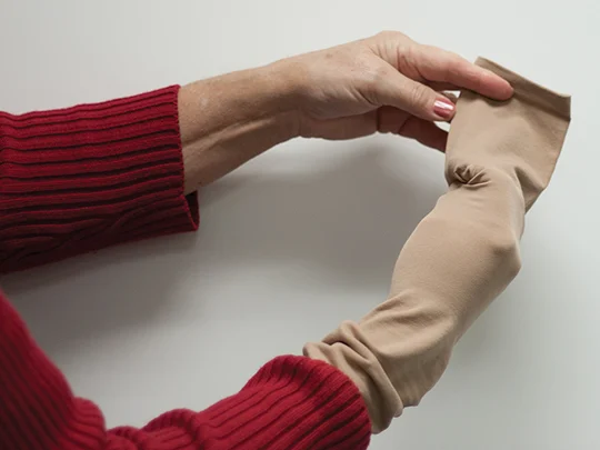 Hands demonstrating first step in donning compression socks.